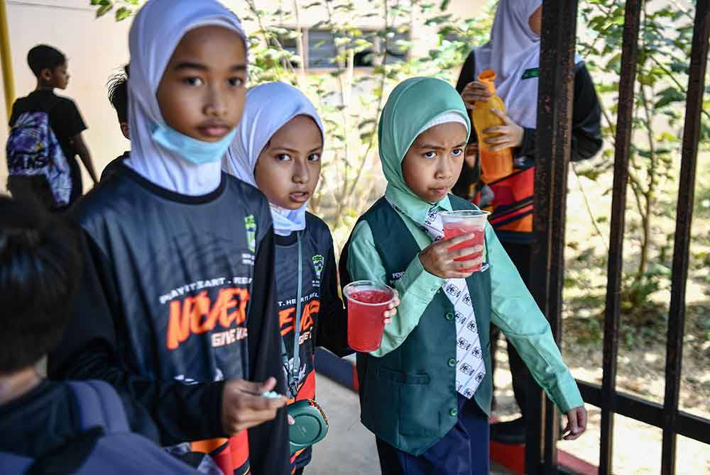 Murid sekolah minum segelas air ekoran cuaca panas ketika tinjauan fotoBernama di sekitar pusat bandar hari ini.