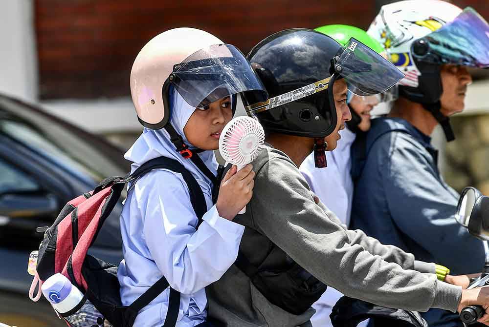 Murid sekolah menggunakan kipas mini mudah alih ekoran cuaca panas ketika tinjauan foto Bernama di sekitar pusat bandar hari ini.