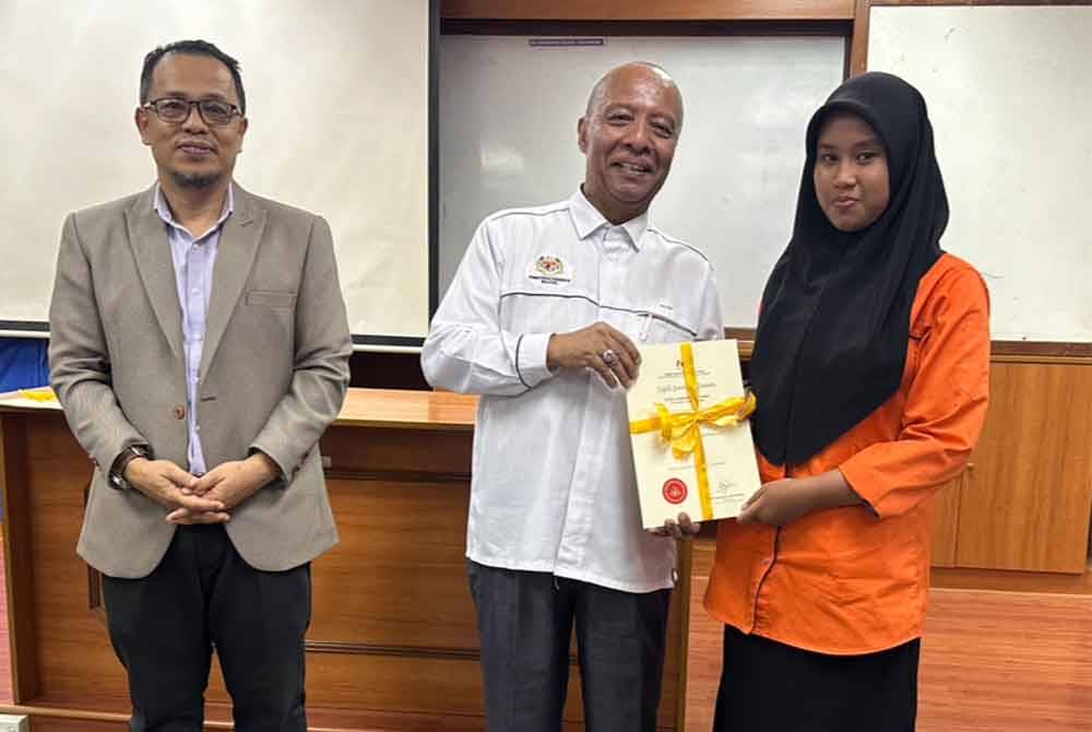 Mohd Nazri (tengah) menyampaikan sijil lantikan duta kepada wakil dari pelajar dari SMK Mulong.