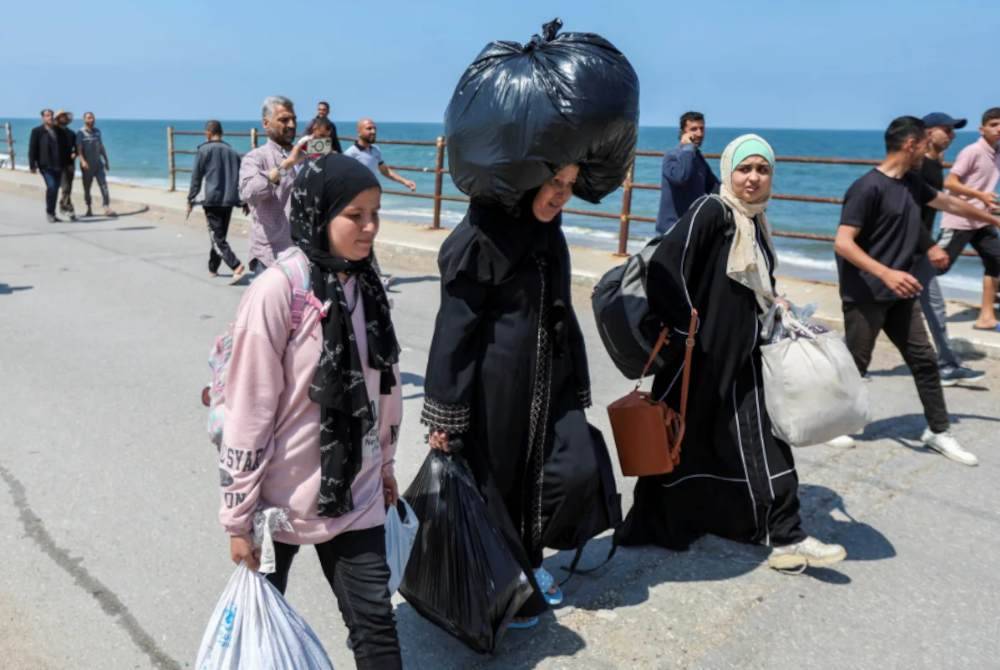 Um Mohammad (tengah) yang menjunjung beg plastik hitam besar sanggup berjalan kaki untuk pulang ke kampung halamannya.