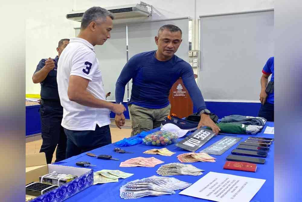 Mohd Shuhaily (kiri) memeriksa barangan yang dirampasa daripada suspek semasa sidang akhbar di IPK Kelantan, Kota Bharu pada Selasa.