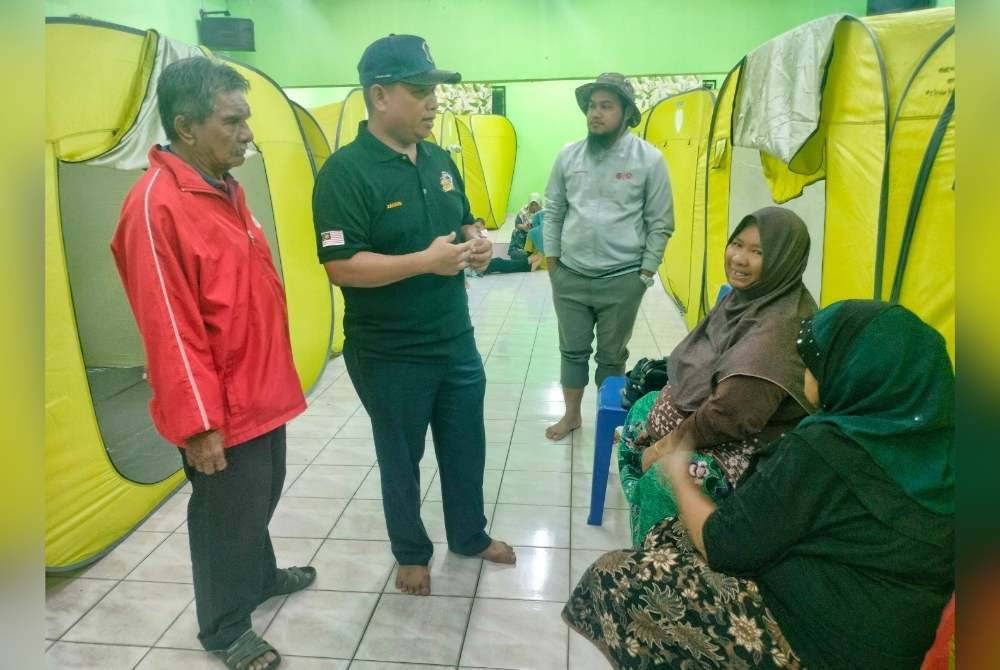 Zahari (dua,kiri) ketika melawat mangsa banjir di PPS Balai Raya Bukit Balai, di sini, pada malam Selasa.
