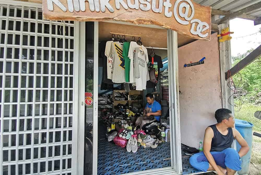 Khairul Anuar (kanan) yang merupakan pelanggan setia Klinik Kasut menunggu Zainuddin menyiapkan kerja-kerja mambaiki kasut yang dihantar ke kedai berkenaan.