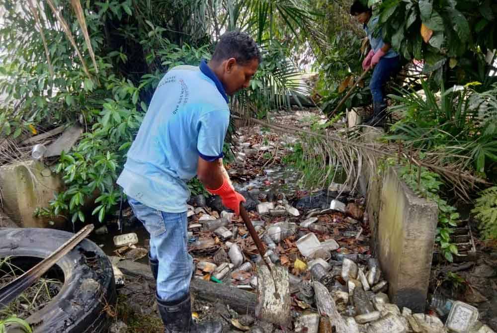 Petugas kebersihan membuang longgokan sampah yang tersumbat dalam longkang di laluan utama Jalan Meru pada Khamis.
