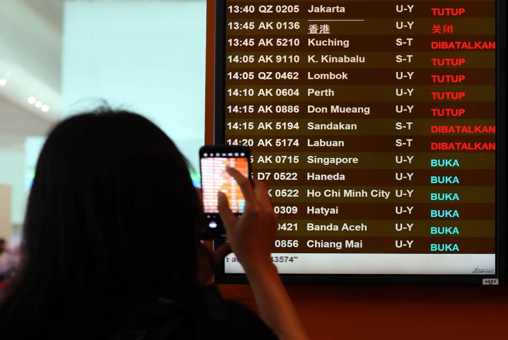 Penumpang pesawat Air Asia merakamkan jadual penerbangan ekoran kesemua penerbangan dari Lapangan Terbang Antarabangsa Kuala Lumpur (KLIA) Terminal 2 menuju ke Sabah, Sarawak dan Brunei telah dibatalkan sehingga lapan pagi esok. Foto Bernama