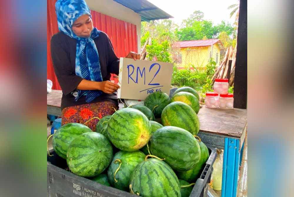 Seorang peniaga runcit menunjukkan harga jualan buah tembikai terkini.