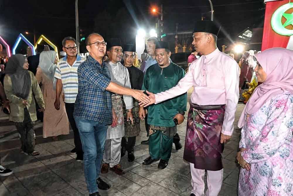 Fairul Nizam (dua dari kanan) bersalam dengan ADUN Machap Jaya, Ngwe Hee Sem yang hadir dalam majlis itu di Pekan Asahan, di sini, pada malam Jumaat.