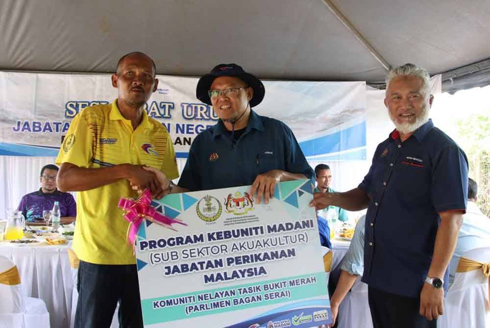 Adnan (tengah) menyampaikan cek cura program Kebuniti Madani kepada peserta terlibat.