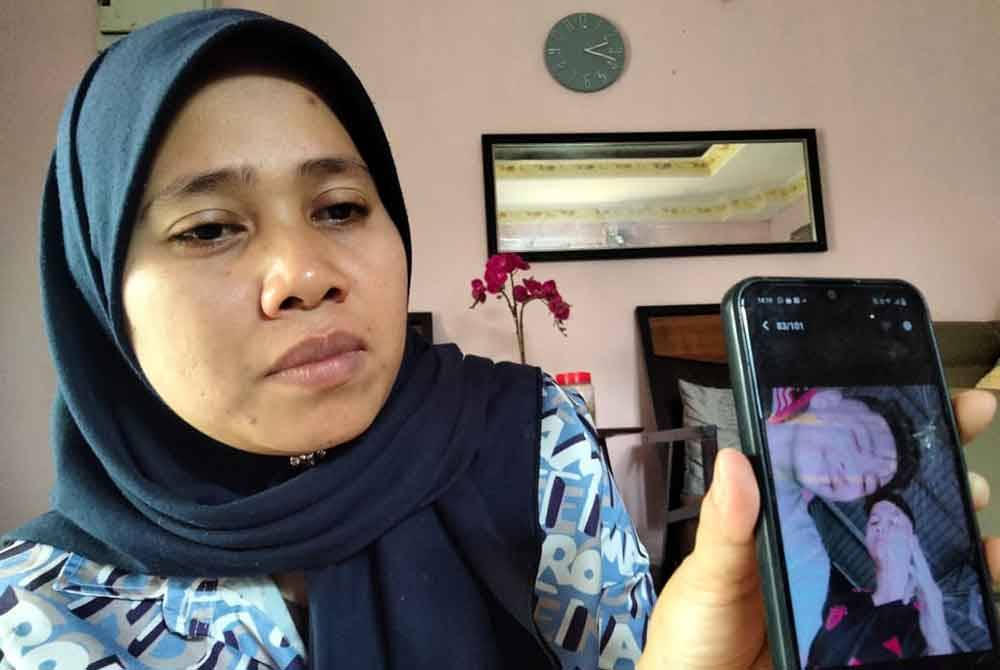 Siti Fairuz menunjukkan gambar Allahyarham Muhamad Fahmi (kanan) yang diambil bersama seorang rakan.