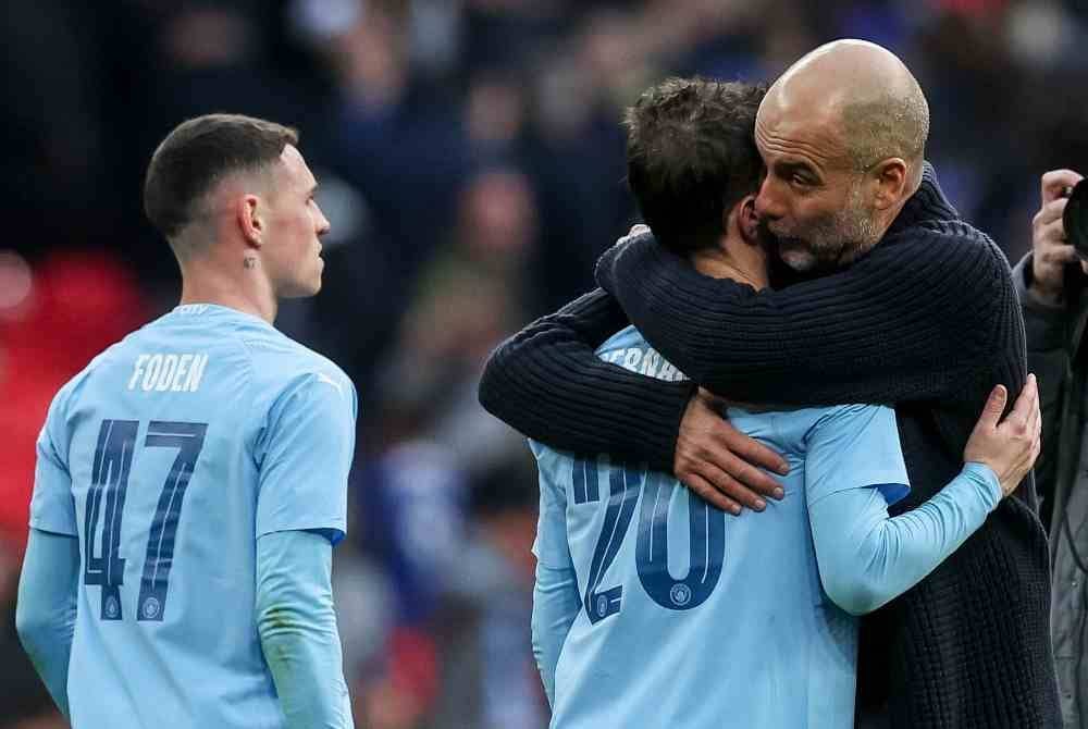Guardiola (kanan) mendakap pemainnya selepas wisel penamat. Foto EPA
