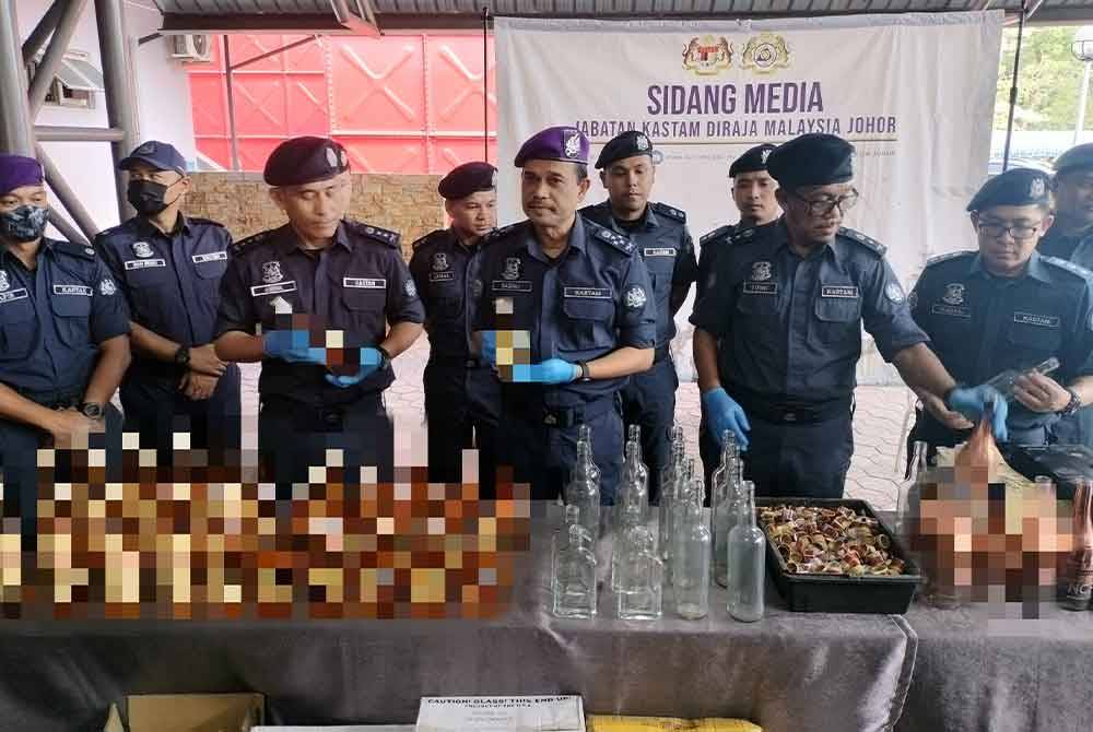 Sazali (tiga dari kanan) menunjukkan minuman keras yang dirampas pada sidang akhbar di Menara Kastam Johor pada Ahad.
