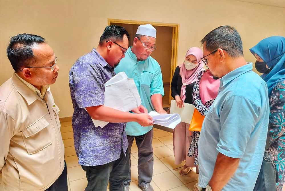 Mohamad Redzwan (dua dari kiri) menyemak dokumen yang dibawa untuk perbincangan bersama MBI di Pejabat JTK Kedah di Alor Setar pada Khamis.