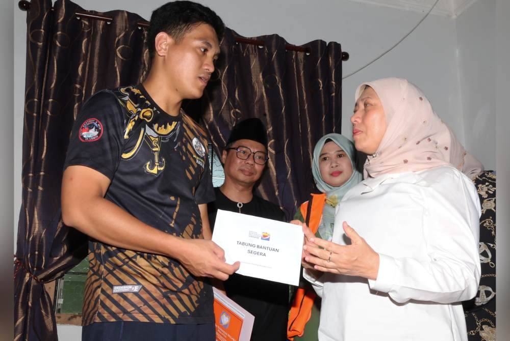 Nancy menyampaikan sumbangan kepada Haslie, suami mendiang Joanna. Foto Bernama