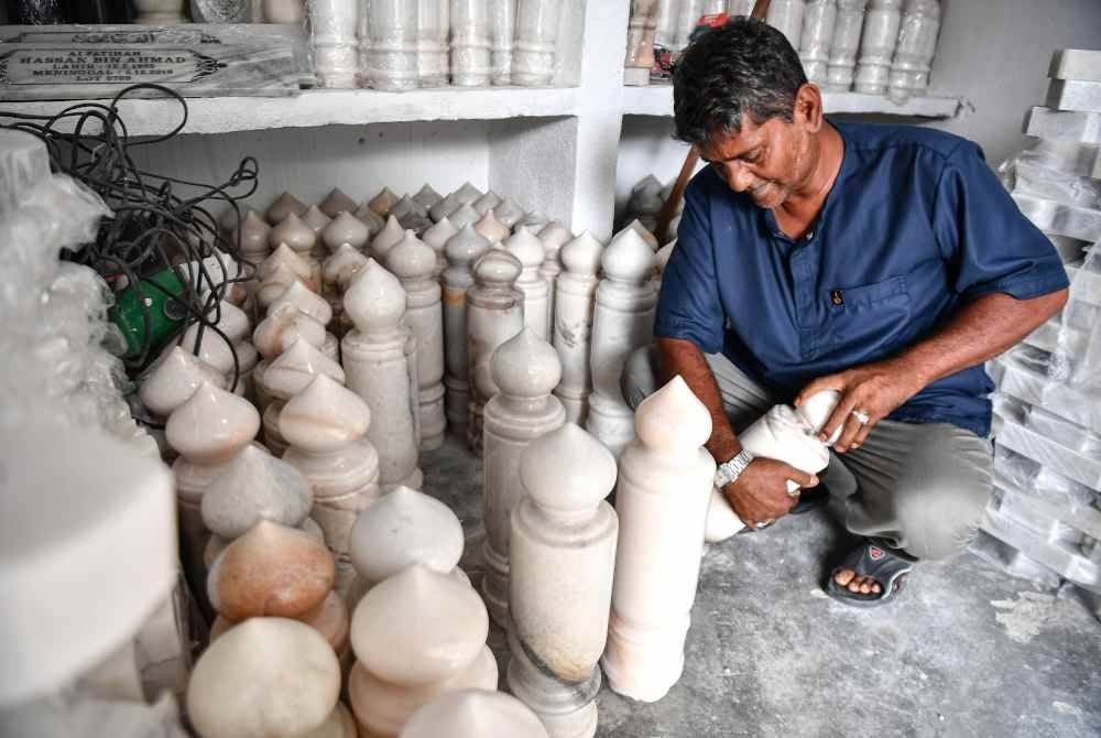 
Baharudin menyusun batu nisan untuk dipasang pada kepok yang ditempah waris keluarga. Foto Bernama