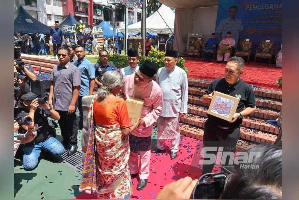 Saifuddin (tengah) berkata sesuatu kepada penerima bakul makanan 'food bank' semasa Karnival Pencegahan Jenayah kolaborasi PDRM dan DBKL dengan rakan strategik serta komuniti setempat di perumahan awam Flat Sri Sabah, Cheras, Kuala Lumpur pada Sabtu. - FOTO:SINAR HARIAN/HISYAMUDDIN AYUB