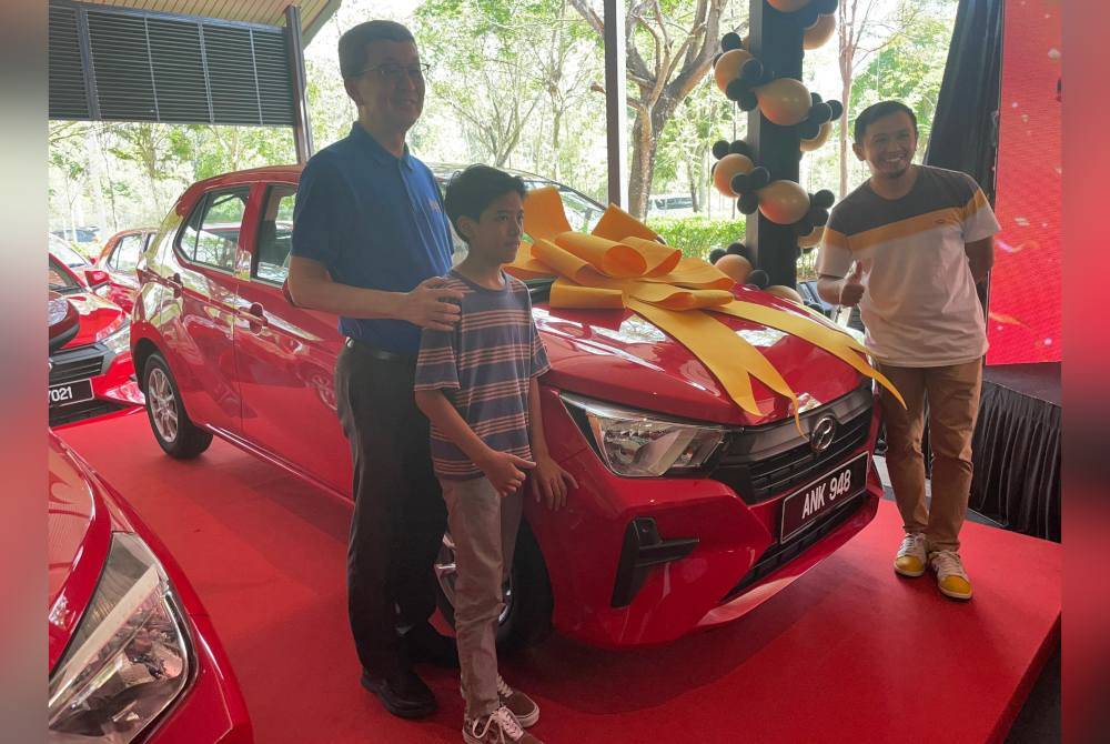 Azwan (kanan) bergambar bersama kereta Axia yang dimenanginya sambil diperhatikan Hock San (kiri) bersama anak Azwan, Mikhail Farish
