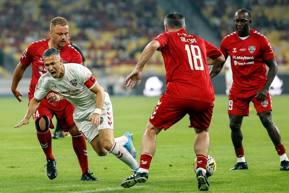 Pemain legenda bola sepak pasukan Liverpool FC, Luis Garcia (tengah) diasak oleh pemain legenda bola sepak pasukan Manchester United Wes Brown (kiri) pada perlawanan 'Battle of The Reds' di Stadium Nasional Bukit Jalil malam Sabtu. Foto Bernama