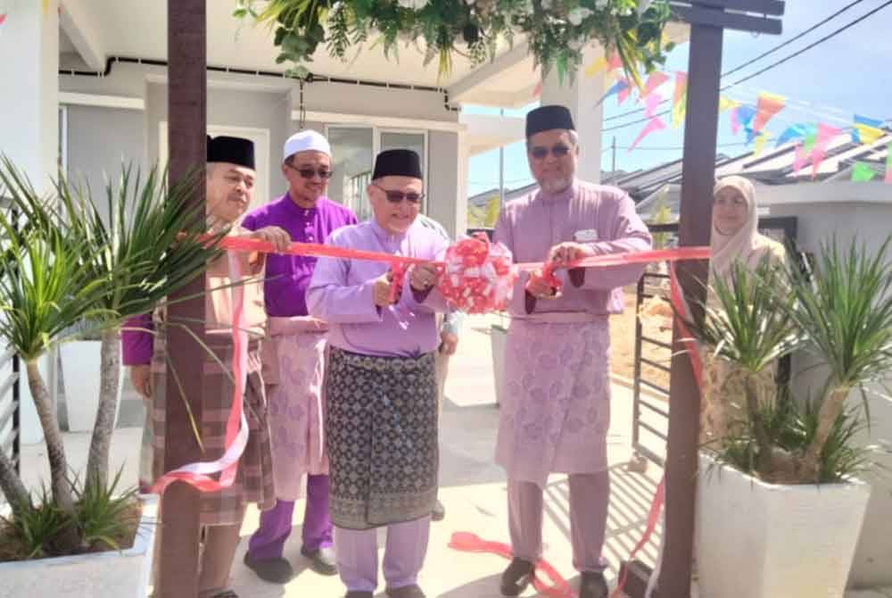 Mohd Amar (dua dari kanan) memotong riben sebelum melawat rumah teres di Taman Kota Jembal