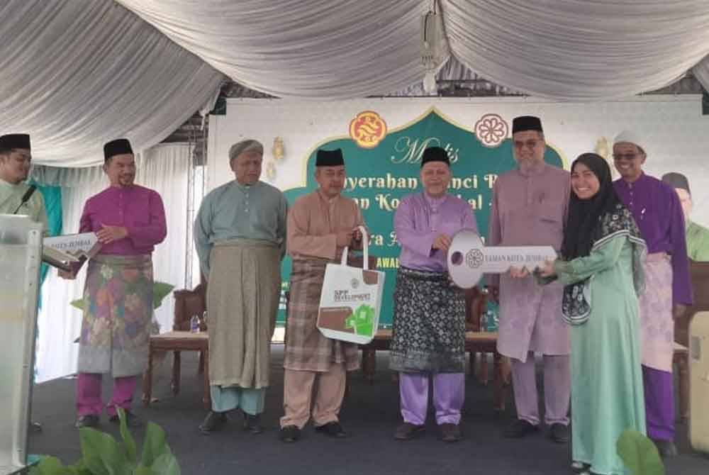 Mohd Amar (lima dari kiri) menyerahkan replika kunci kepada seorang pembeli rumah di Taman Kota Jembal, Kota Bharu
