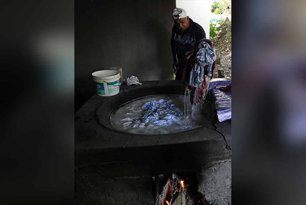 Raman merendam pakaian terutama dhotis berwarna putih dalam air panas selama beberapa minit, untuk membunuh kuman dan menyerlahkan keputihan. Foto Bernama
