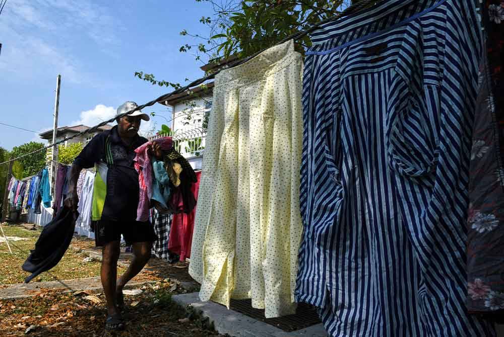 Raman menjemur pakaian yang dibasuh. Foto Bernama