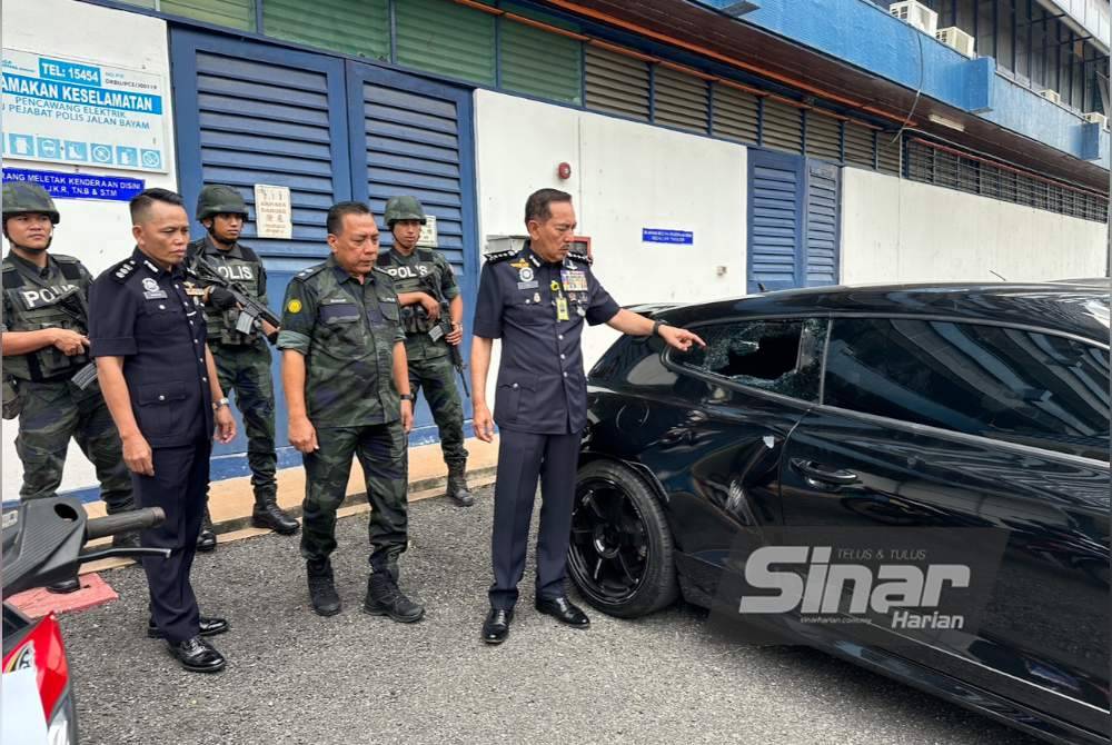 Muhamad Zaki (kanan) melihat kesan cermin pecah pada Volkswagen Scirocco.
