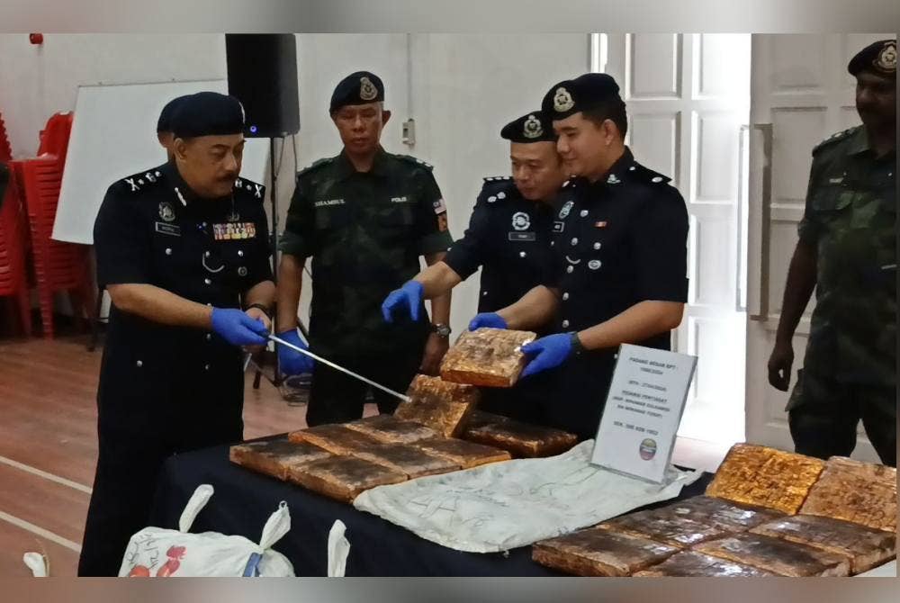 Baderulhisham (kiri) melihat ketulan ganja mampat yang berjaya dirampas pada Sabtu di kawasan laluan keselamatan sempadan Malaysia-Thailand di Chuping.