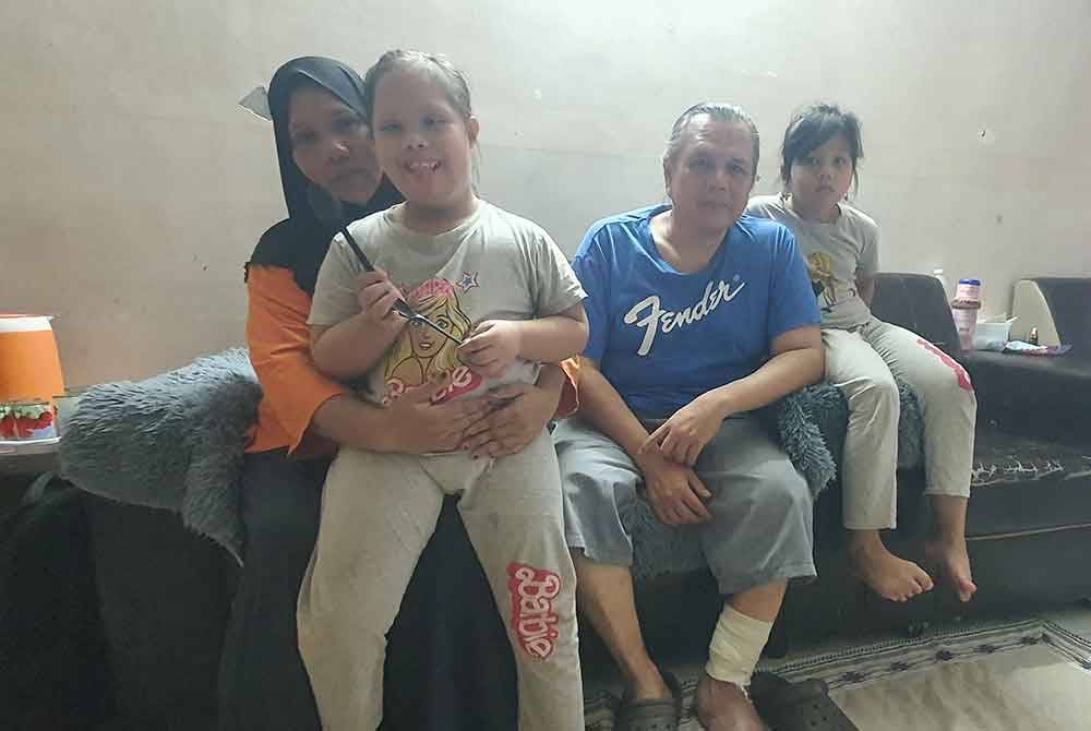 Noraniza memangku anak OKUnya bersama suami yang menghidapi kencing manis kronik dan anak bongsu mereka.