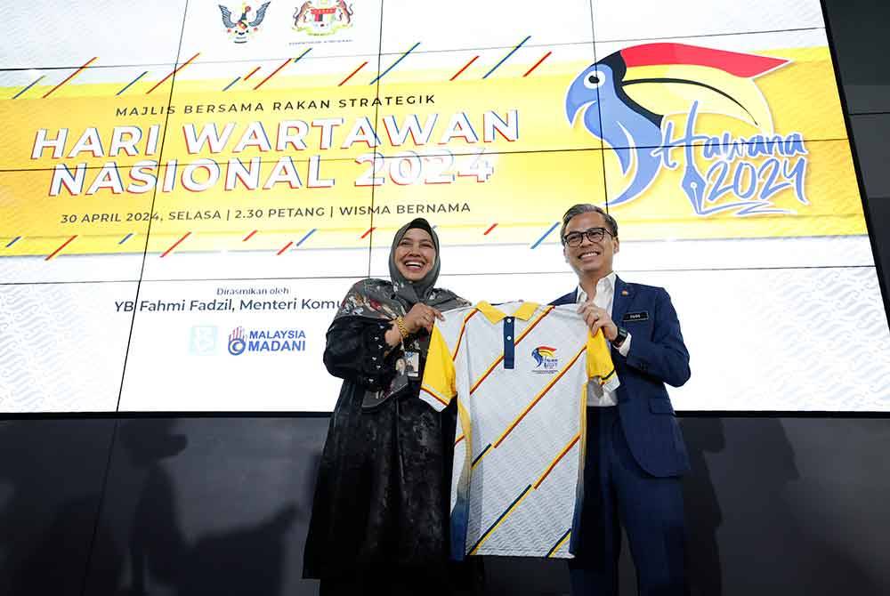 Fahmi (kanan) menerima baju sempena penganjuran Hawana 2024 yang disampaikan oleh Nur-ul Afida pada Majlis Bersama Rakan Strategik Hawana 2024 di Wisma Bernama pada Selasa.