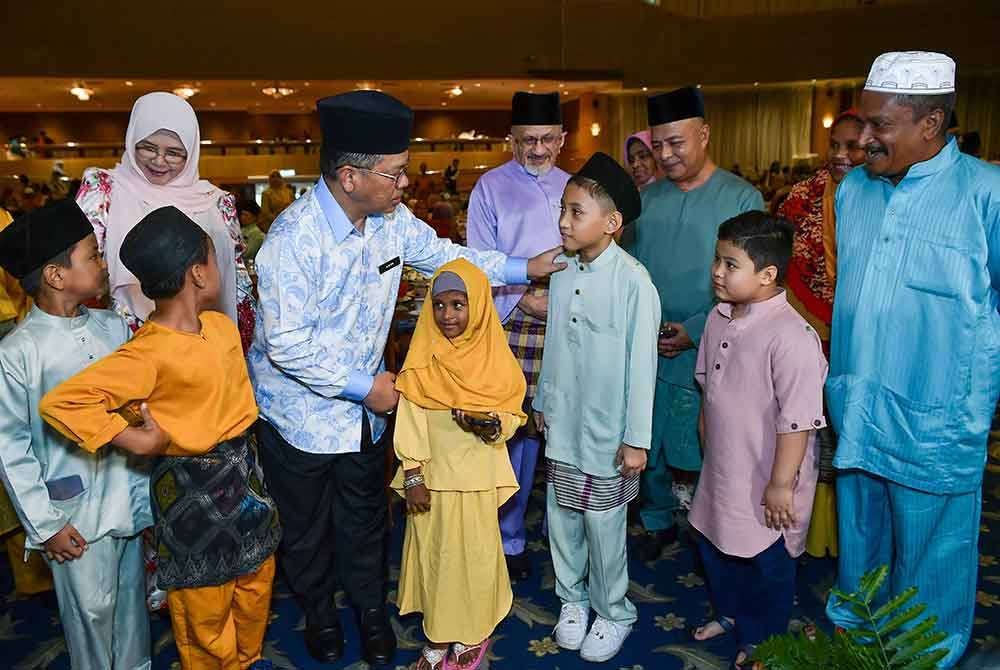 Mohd Na'im (tengah) menyerahkan sumbangan kepada anak-anak asnaf yang hadir pada majlis Rahmah Syawal Majlis Agama Islam Wilayah Persekutuan (MAIWP): Jalinan Aidilfitri Bersama Asnaf MAIWP di Dewan Perdana Felda di Kuala Lumpur pada Selasa. Foto Bernama