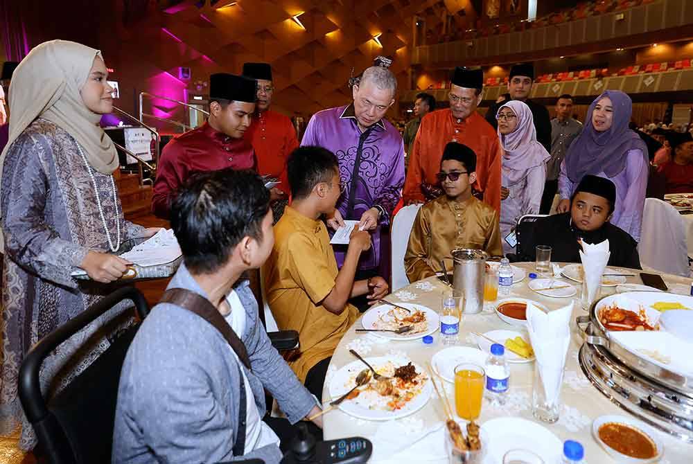 Fadillah menyampaikan sumbangan bantuan kepada OKU dan Pelajar asnaf UiTM. Foto Bernama