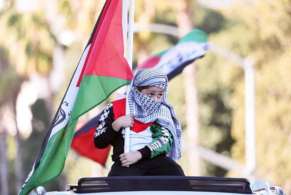 Seorang penunjuk perasaan termuda mengibarkan bendera Palestin semasa 'Perarakan Kanak-Kanak Demi Palestin' di Los Angeles, California. - AFP