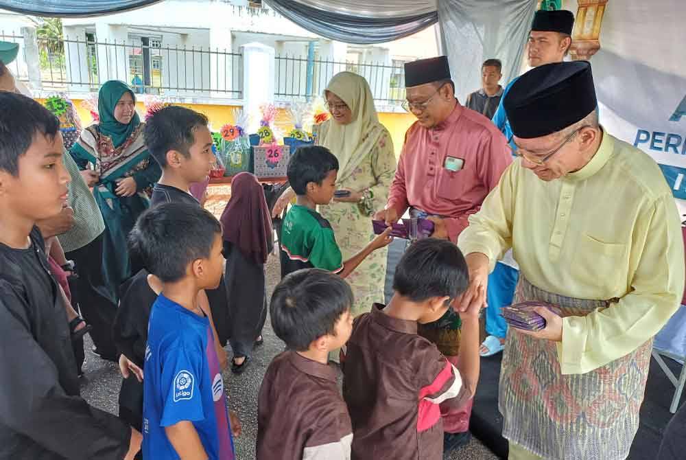 Saifuddin (kanan) bersama Andansura mengagihkan sumbangan raya kepada kanak-kanak yang hadir pada majlis rumah terbuka PN Parlimen Indera Mahkota di Kampung Padang.
