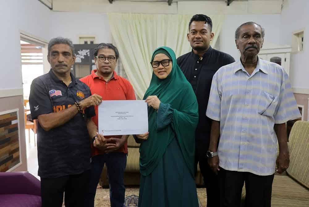 Noorul Ariffin (kiri) menyerahkan cek khairat kematian kepada Siti Norkhanah Mohammed Yatim (tiga dari kanan) balu kepada legenda bola sepak negara era-1970-an, Allahyarham Khalid Ali di kediamannya di AU4 Taman Seri Keramat hari ini - Foto: Bernama