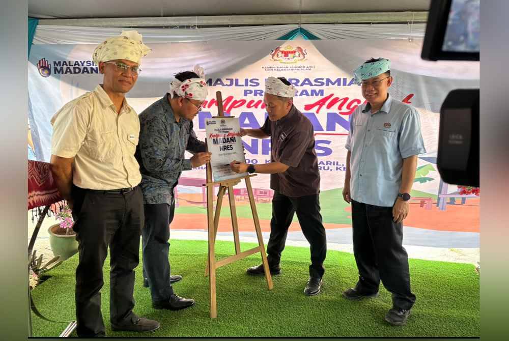 Nik Nazmi (dua dari kanan) menandatangani plak sebagai simbolik perasmian Program Kampung Angkat Madani di Kampung Aril.
