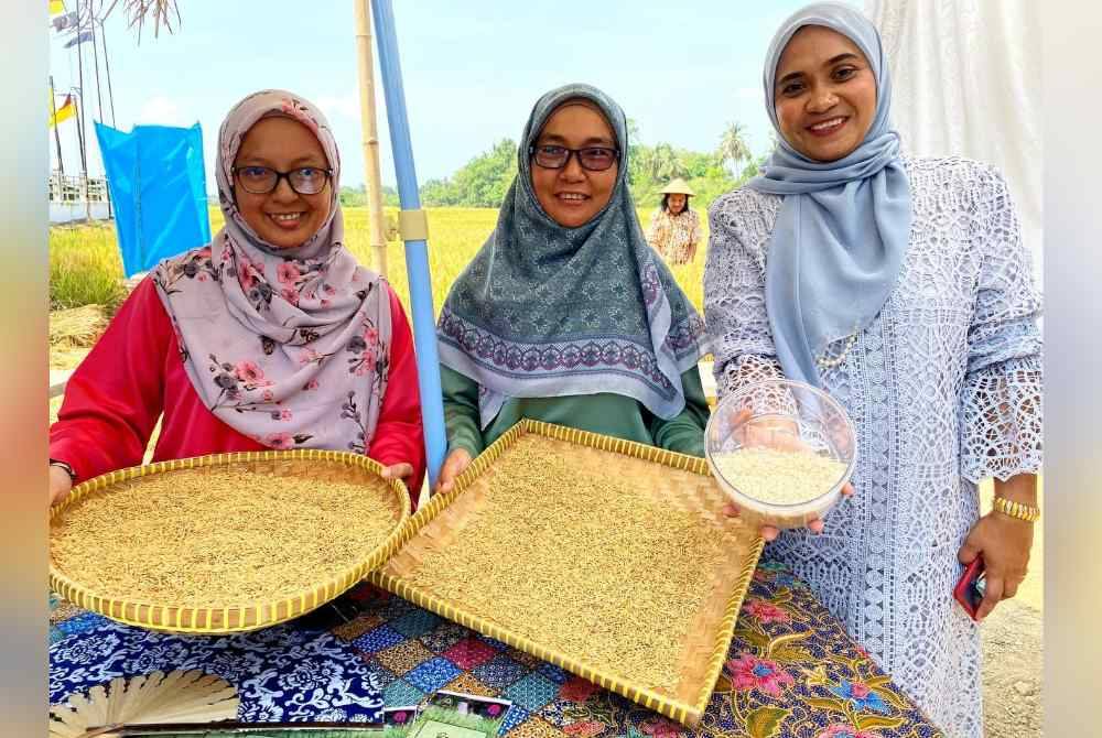 
Tiga wanita menunjukkan beras dan padi yang tanamannya menggunakan air semata-mata.