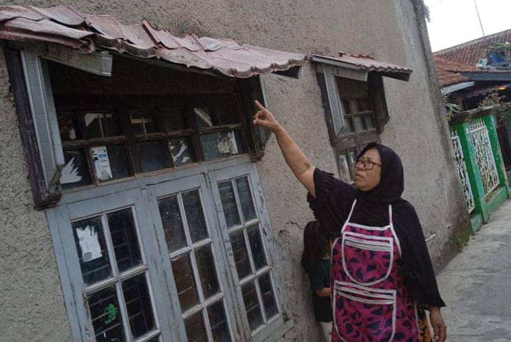 Penduduk menunjukkan keadaan rumah yang terjejas akibat gempa bumi. Foto BNPB