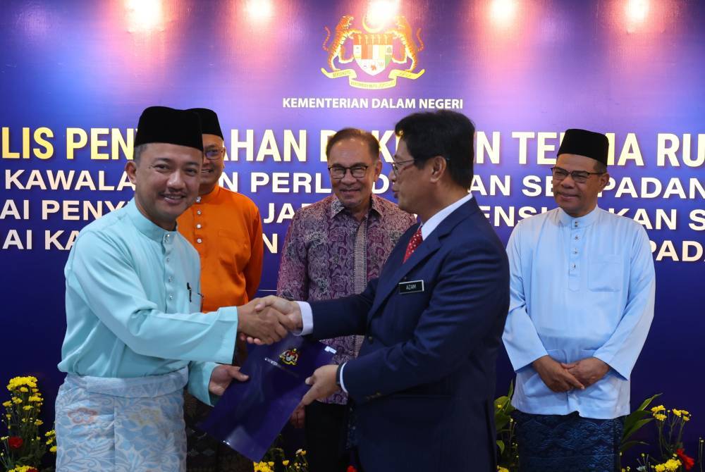 Anwar (tengah) menyaksikan majlis penyerahan dokumen terima rujukan MCBA dan sambutan Aidilfitri di Kompleks Kementerian Dalam Negeri pada Khamis. Foto Bernama