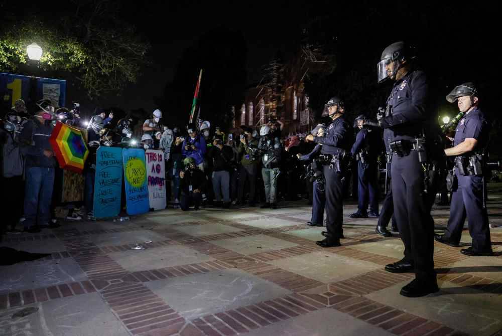 Pelajar pro-Palestin berdiri teguh selepas polis melanggar perkhemahan mereka di kampus Universiti California, Los Angeles (UCLA) pada Khamis. Foto AFP
