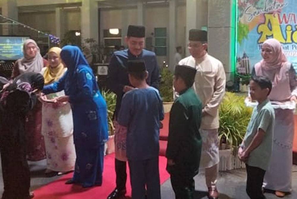 Muhamad Zaki (tiga, kanan) menyampaikan duit raya kepada kanak-kanak sempena Majlis Sambutan Warna Warni Aidilfitri Ibu Pejabat Polis Daerah (IPD) Pasir Mas, di sini pada Jumaat.