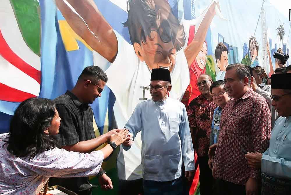 Anwar bersalaman dengan pengunjung yang hadir ke Program Madani Rakyat 2024 Zon Utara dan Majlis Sambutan Aidilfitri Madani 2024 Peringkat Pulau Pinang di Tapak Pesta Pulau Pinang.