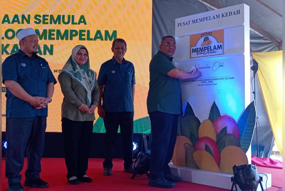 Muhammad Sanusi (kanan) menandatangi plak perasmian penjenamaan semula kepada Pusat Mempelam Kedah pada Majlis Penjenamaan Semula Pusat Teknologi Mempelam Sala Kanan pada Ahad.