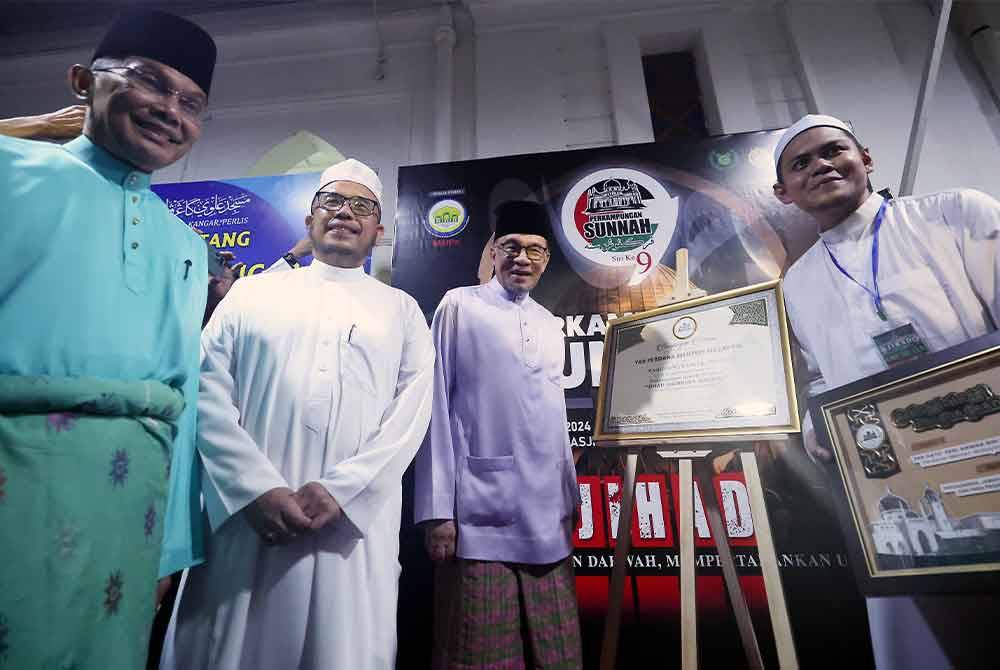 Anwar menandatangani plak sempena ucap tama Program Perkampungan Sunnah Siri ke-9 di Masjid Alwi
baru-baru ini. Turut hadir (dari kiri): Mohd Shukri dan Mohd Asri. - Foto Bernama