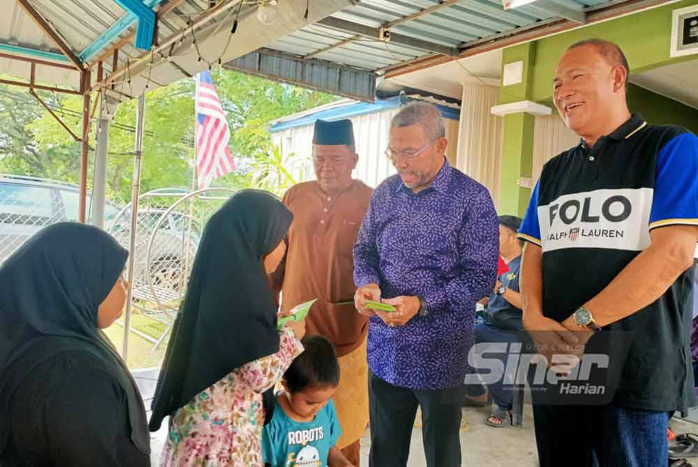 Mohd Azhar (tengah) menyampaikan duit raya kepada kanak-kanak yang hadir ke Majlis Rumah Terbuka Aidilfitri Pekita di Taman Kinta Perdana, Lahat pada Ahad.