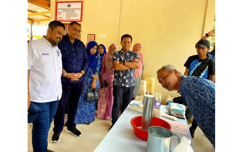 Manndzri (kiri) melihat demonstrasi penghasilan lateks oleh Mohd Azlan (kanan).