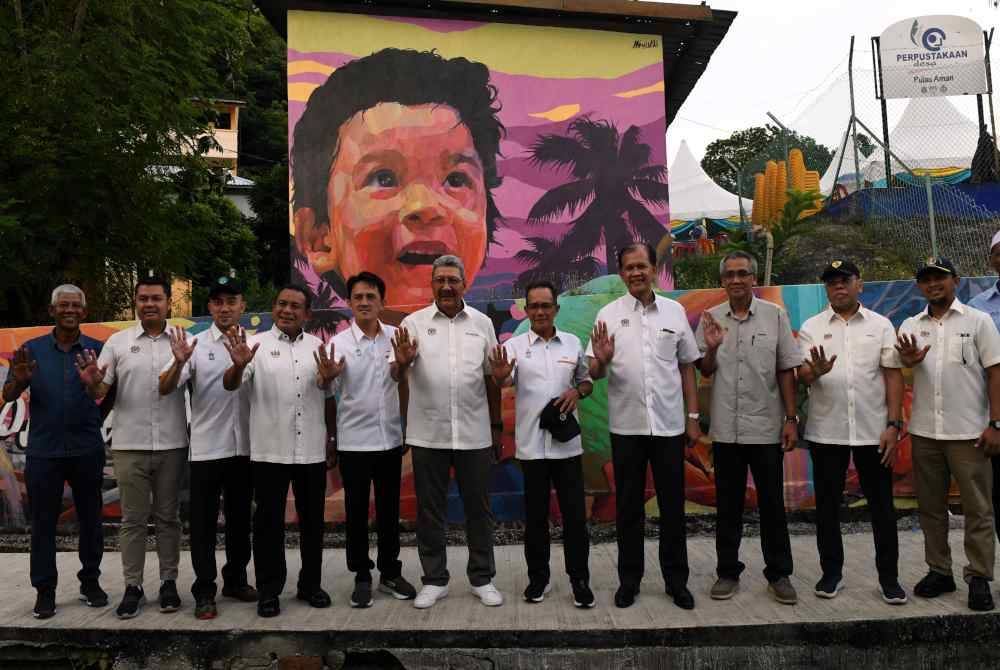 Wan Ahmad Dahlan (enam, kiri) bersama tetamu bergambar di hadapan lukisan mural di Pulau Aman pada Majlis Pelancaran Kampung Angkat Madani JPA: Transformasi Pulau Aman di Pulau Aman pada Ahad. Foto Bernama