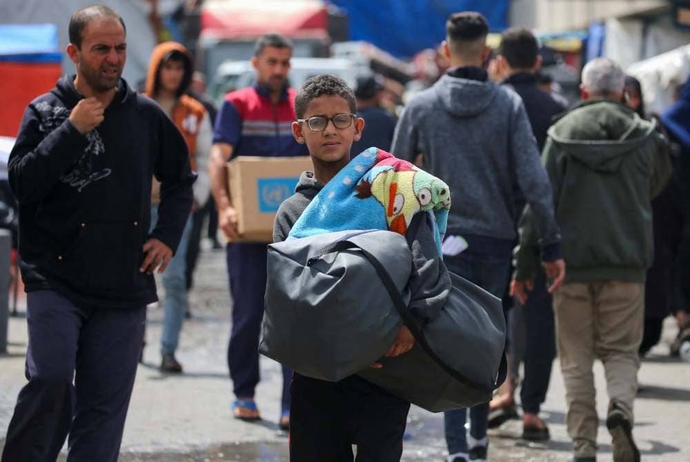 Rakyat Palestin di Rafah membawa barang untuk berpindah susulan konflik antara Israel dan Hamas. Foto AFP