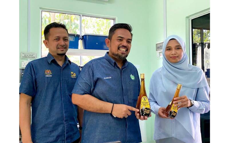Nur Izzatie (kanan) bersama Pengerusi RISDA, Manndzri Nasib (tengah) menunjukkan produk madu kelulut yang dihasilkan melalui inisiatif AET.