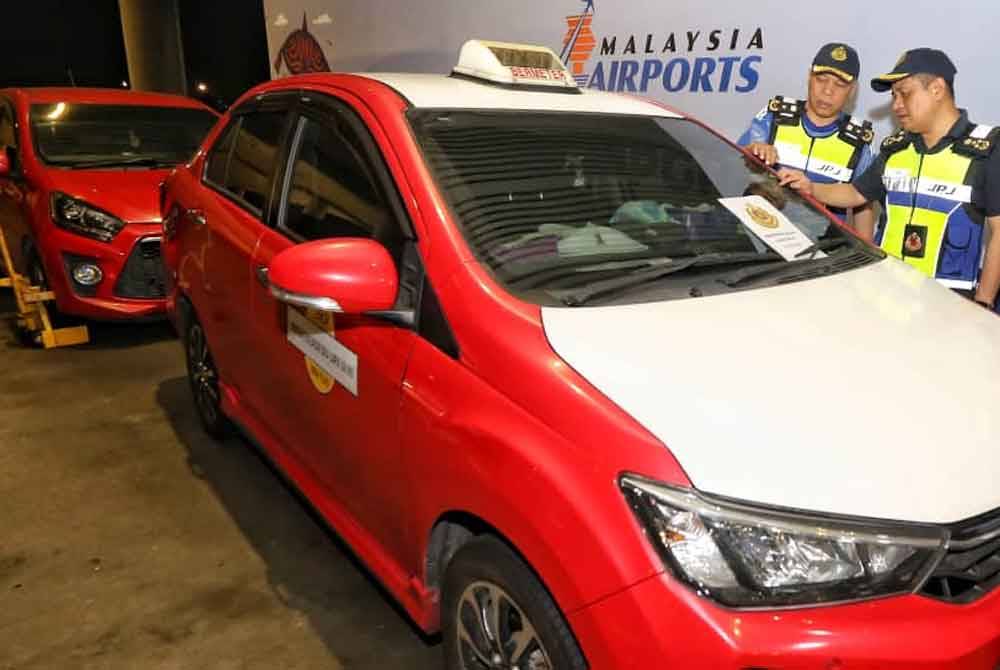 Aedy (kanan) melihat cukai jalan sebuah teksi yang ditahan semasa Op Khas Ulat dan e-Hailing di KLIA1 dan KLIA2.