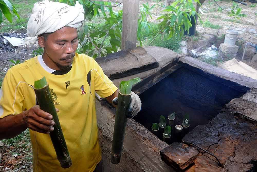 Peniaga lemang, Mohd Zailani Mohd Nor, 49, memasukkan lemang ke dalam dapur relau ciptaannya ketika ditemui di rumahnya di Kampung Alor Belanga dekat Kampung Alor Keladi.